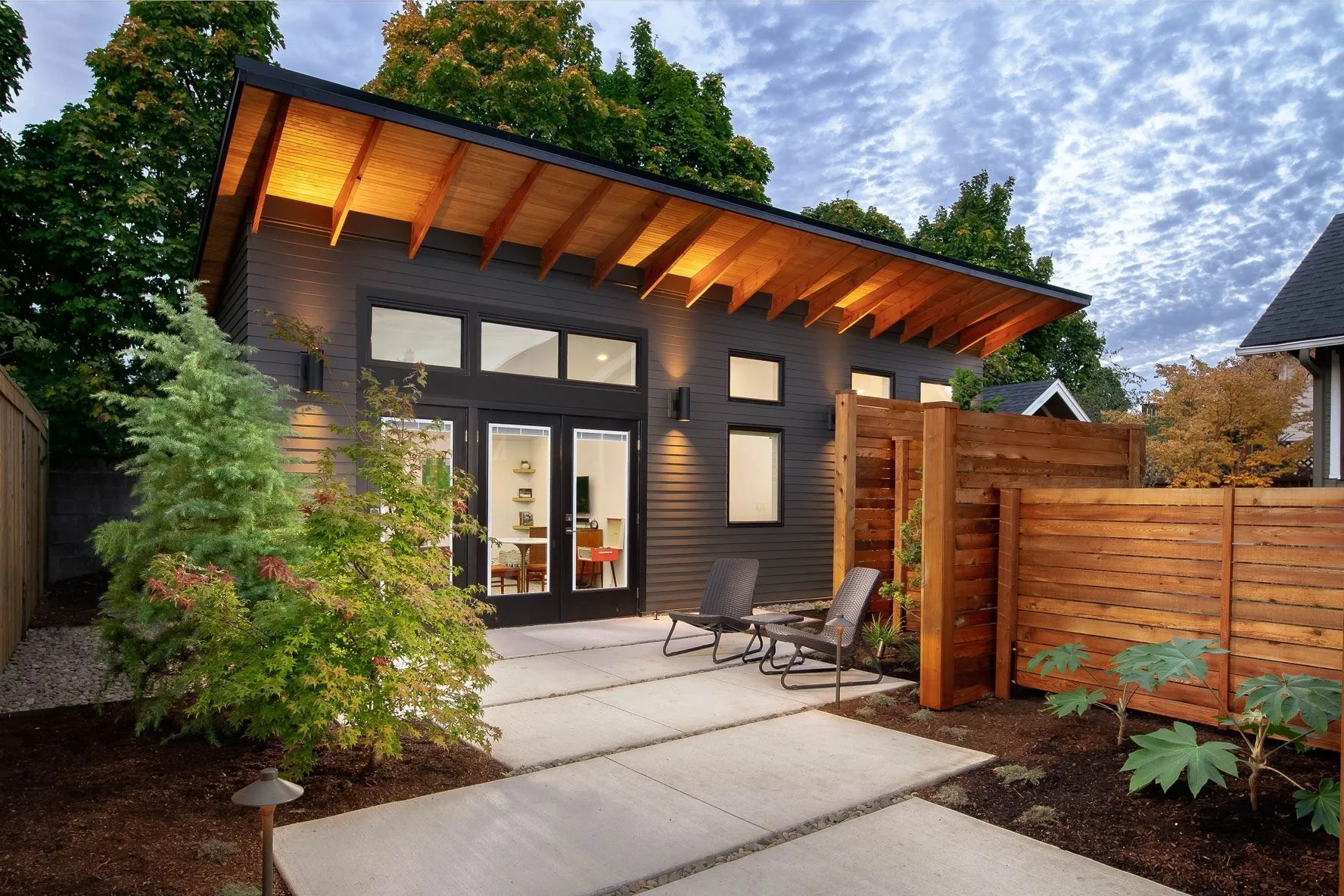 Modern backyard office with sleek exterior design, wooden accents, large windows, and landscaped garden - Cresttel construction and renovation services.