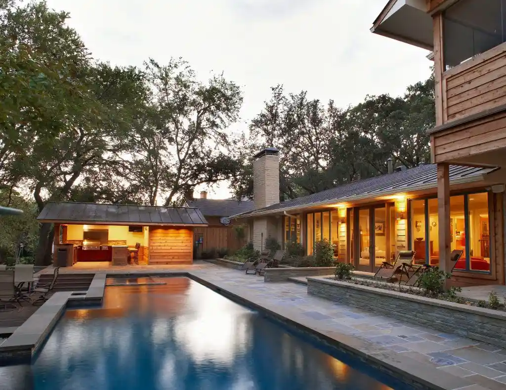 Modern luxury house with swimming pool and outdoor kitchen at sunset, showcasing Cresttel's premium residential construction and design services